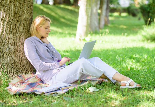 Natural environment office. Work outdoors benefits. Woman with laptop computer work outdoors lean on tree trunk. Education technology and internet concept. Girl work with laptop in park sit on grass