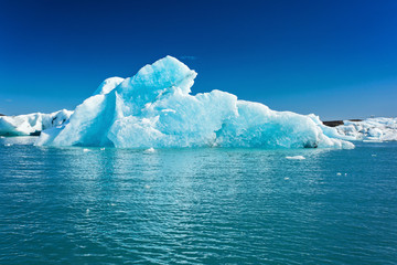 Blue iceberg in the water against the blue sky