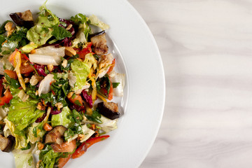 Eggplant salad with vegetables and walnuts on a white plate.