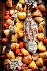Top view of homemade seabream with tomatoes and potatoes