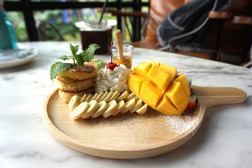 Mixed fresh fruits serving with homemade pancake with glass of honey