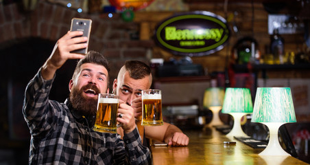 Taking selfie concept. Send selfie to friends social networks. Man in bar drinking beer. Take selfie photo to remember great evening in pub. Online communication. Man bearded hipster hold smartphone