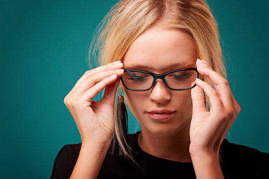 Portrait of intrigued charming calm and feminine young woman with blond hair putting on eyewear checking sight and lens dioptria