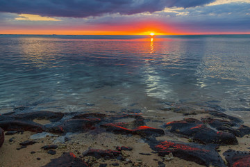 The burning sunset over Indian ocean paints stones ashore in red color, Mauritius island