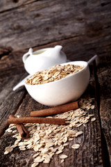 Oatmeal or oat flakes with milk and cinnamon on dark wooden table