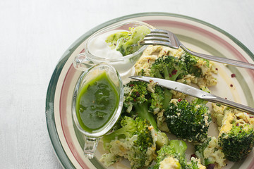 fried broccoli with egg on a plate on a gray background with sauces