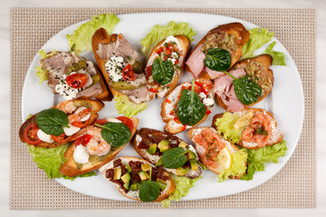 Meat sandwiches with vegetables in an assortment on a white dish.