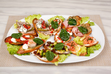 Meat sandwiches with vegetables in an assortment on a white dish.