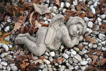 A weathered sandstone sculpture of a sleeping angel.