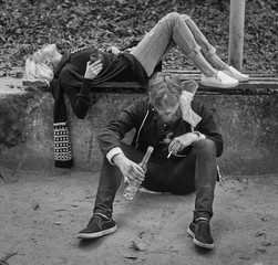 Fototapeta premium Alco addiction concept. Depressed and hopeless couple sitting after using drunk alcohol on the street