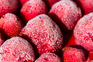 Close-up of a handful of frozen strawberries covered by frost.