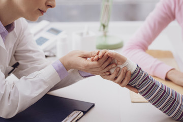 Fototapeta premium Pediatrician examining a young girl with an injured wrist