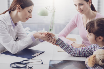 Pediatrician examining a young girl with an injured wrist