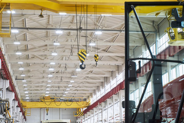 the ceiling of a large factory room after repair with artificial lighting and large yellow girder cranes on a bright day