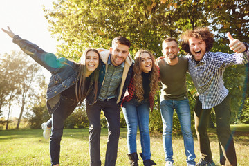Young people laugh while standing in a park in spring. 