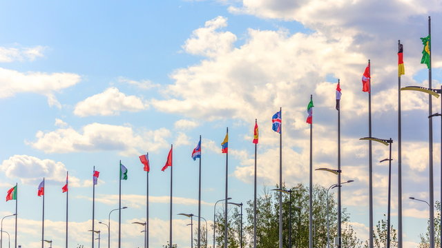 National flags of the countries participating in the finals of the FIFA World Cup against a blue cloudy sky.