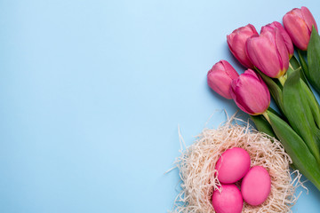 Pink flowers tulips with easter eggs on a blue background
