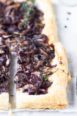Mushroom tart, puff pastry pie with cream cheese, mushrooms, onion and thyme. Light concrete background. Copy space.