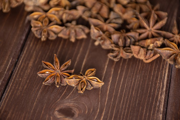 Group of two whole dry brown star anise fruit in a focus on brown wood