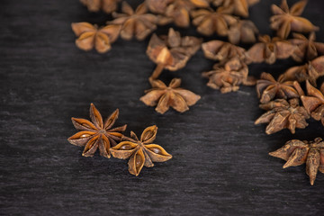 Fototapeta na wymiar Group of two whole dry brown star anise fruit in a focus and a stack on grey stone