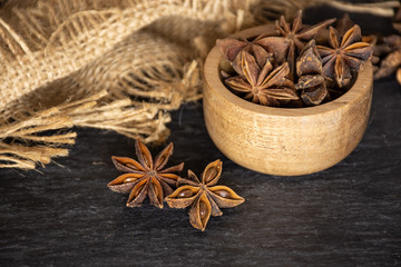 Lot of whole dry brown star anise fruit with wooden bowl on grey stone