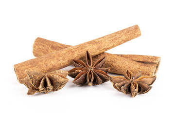 Group of three whole dry brown star anise fruit with two cinnamon sticks isolated on white background