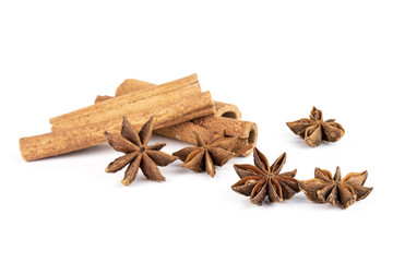 Group of five whole dry brown star anise fruit with three cinnamon sticks isolated on white background