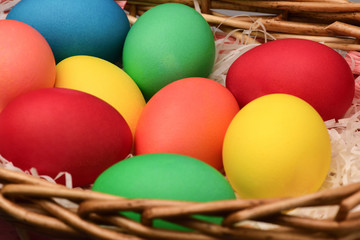 Fototapeta na wymiar Close-up of Easter eggs of different colors lie in a wicker basket. Horizontal photography