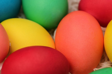 Close-up of Easter eggs of different colors lie in a wicker basket. Horizontal photography