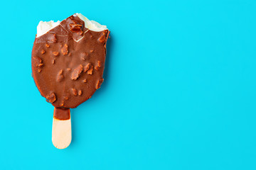 chocolate outer ice cream with peanuts on a blue background with some bites