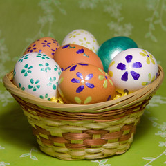 Colored  easter eggs  with flower  laying in wood basket