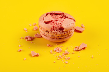 broken pink macaroon on yellow background
