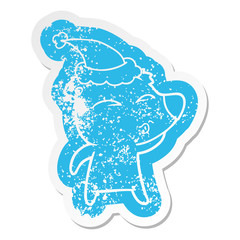 cartoon distressed sticker of a whistling bear wearing santa hat