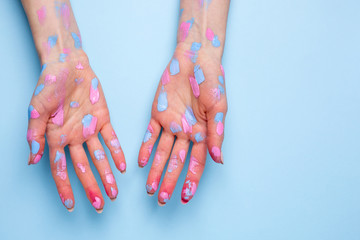 Women's hands with watercolor brushstrokes on blue background