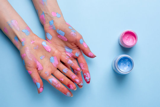 Women's hands with watercolor brushstrokes on blue background