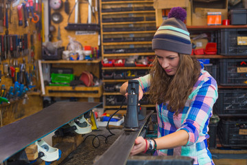 Pretty girl repairing ski in the workshop