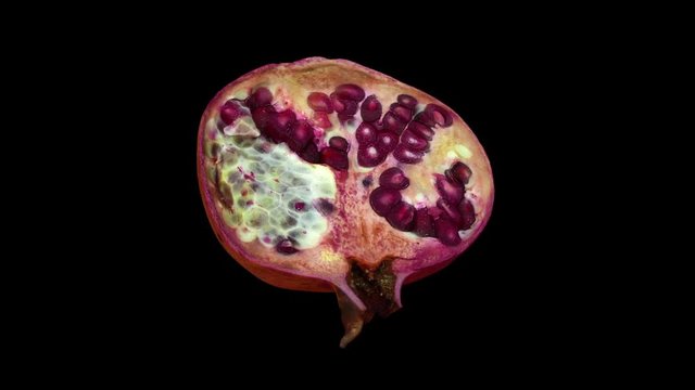 Realistic render of a rotating pomegranate (cut in half) on black background. The video is seamlessly looping, and the object is 3D scanned from a real pomegranate.