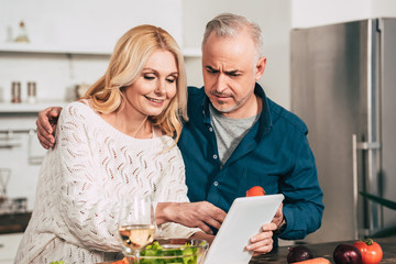 selective focus of couple looking at digital tablet in kitchen