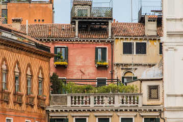 Beautiful old balconies with red flowers vases in Venice, Italy