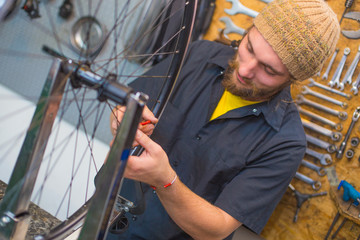 Bearded guy repairing bicycle in the workshop