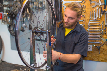Fototapeta na wymiar Blue eyed guy repairing bicycle in the workshop