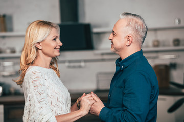 Obraz premium happy wife and husband holding hands and smiling at home