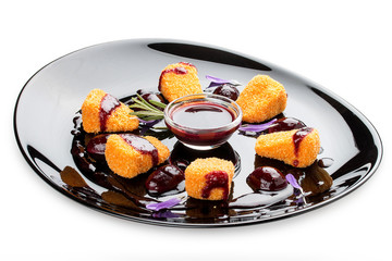 Fried Camembert with cranberry sauce on a glossy black plate
