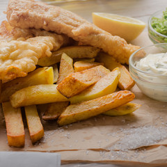 Traditional British street food fish and chips with tartar sauce and mushy peas on paper plate