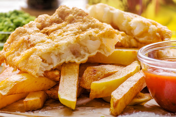 Traditional British street food fish and chips with ketchup sauce on parchment paper