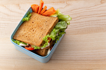 Flat lay with healthy sandwich in plastic container on wooden table. Daily office or school lunch concept