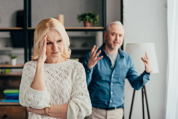 Obraz premium selective focus of woman holding head while husband arguing on background