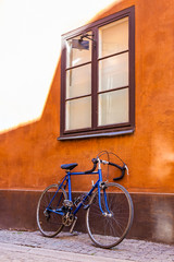 Fototapeta na wymiar Blue sport bicycle standing near the orange building facade wall with big window with brown window frame