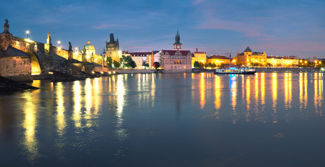 Fototapeta na wymiar Panoramic image of illuminated Charles Bridge reflected in Vltava river at night