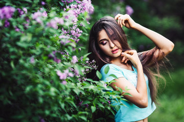 Wonderful spring. Cute young girl posing on nature near lilac blooming.